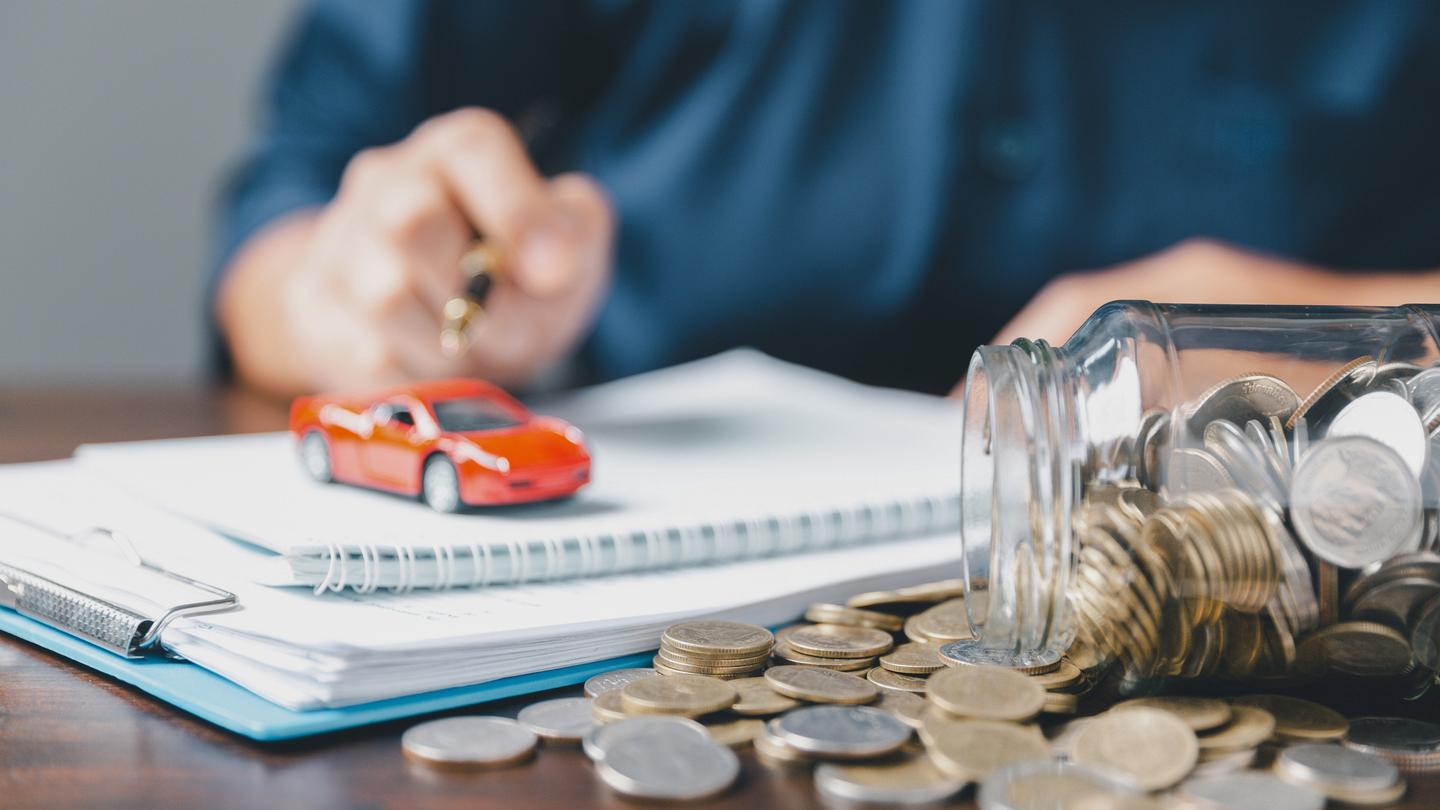 person sat at desk with coins spilling out of a jar