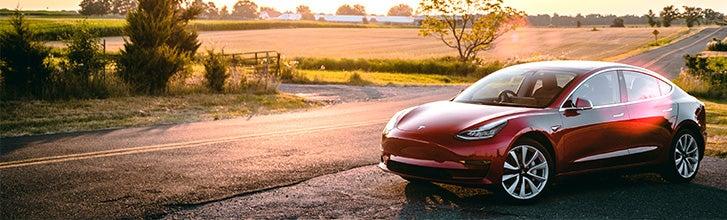 Red Tesla Model 3 in the countryside