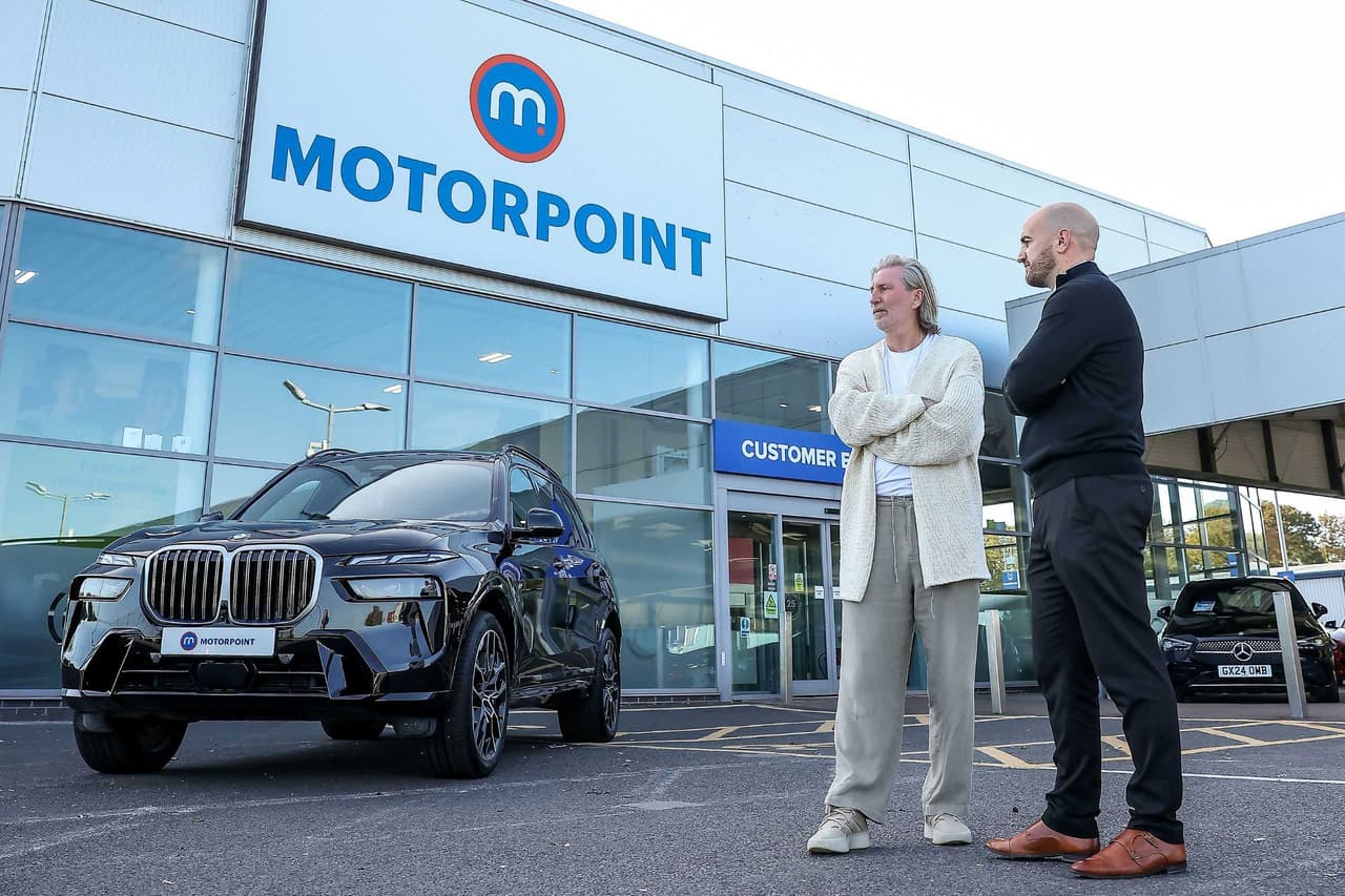 Image of Savage, pictured alongside Lee Watson, general sales manager at Motorpoint Peterborough outside the store when collecting a black BMW X7