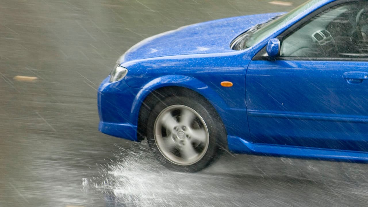 Blue car (Mazda Protege MP3) driving fast in the rain, water splashing from tyre