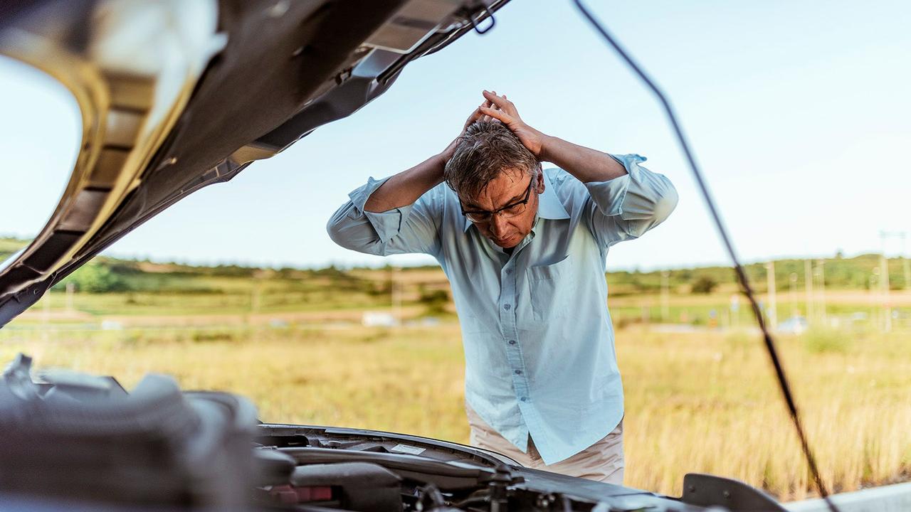 Driver looking shocked at car's broken engine