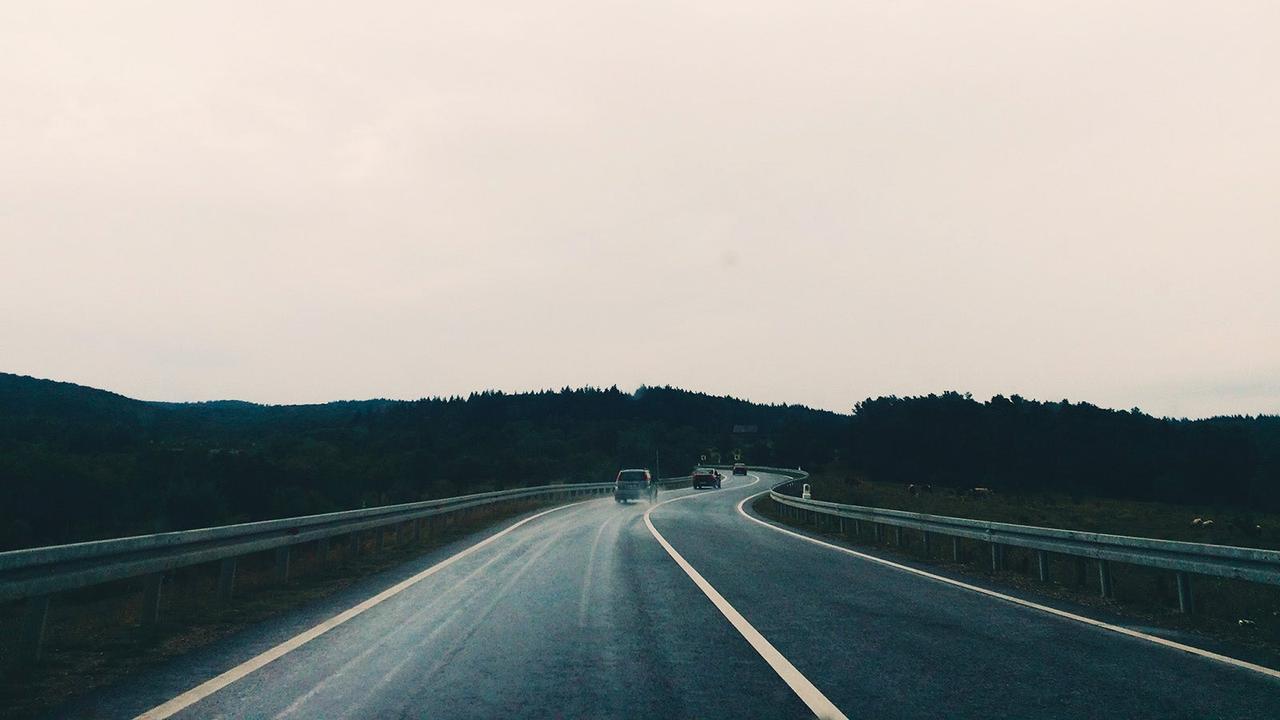 Cars drive off into the distance on a wet road