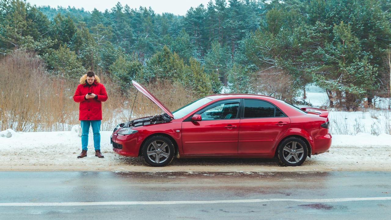 Man standing near broken car at roadside snowed winter weather stock photo