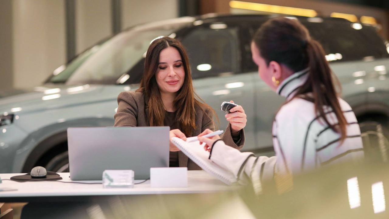 Woman signing a finance contract with car salesperson