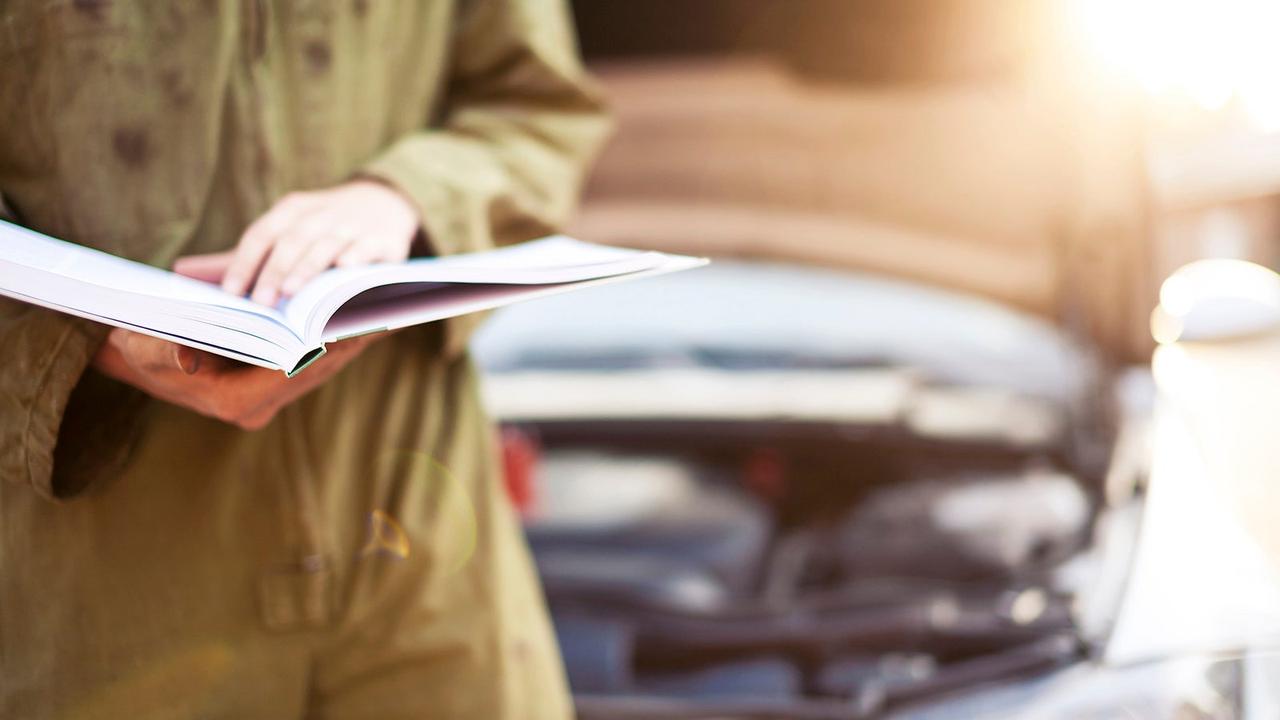 Mechanic reading a car handbook