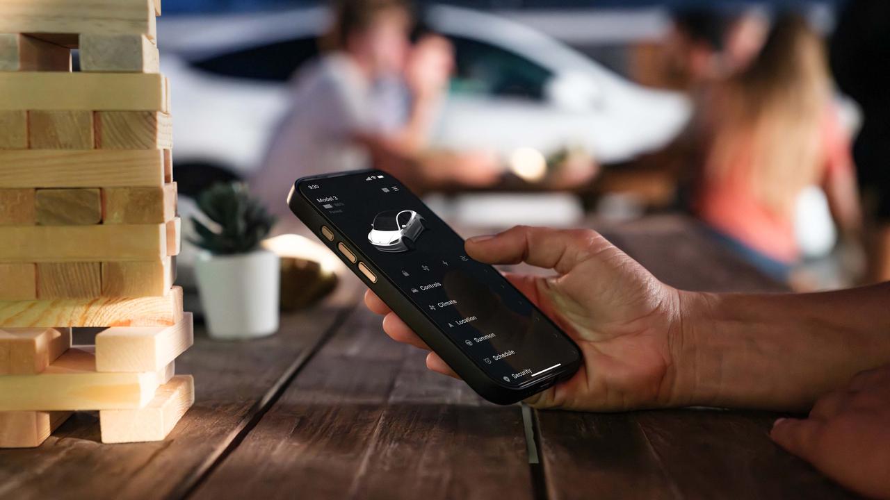 Person using Tesla app on a table next to a jenga tower