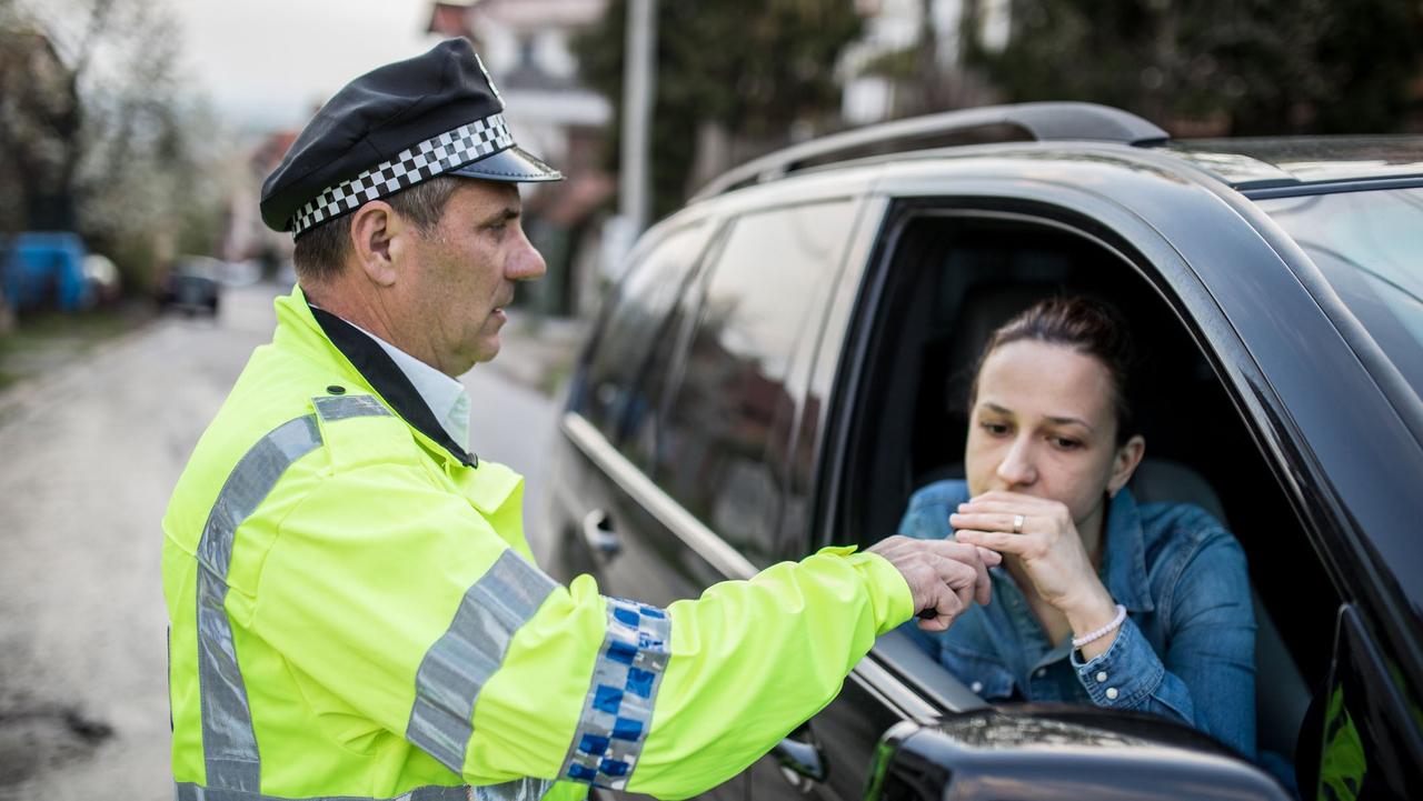 Female driver doing a roadside breath test with a police officer