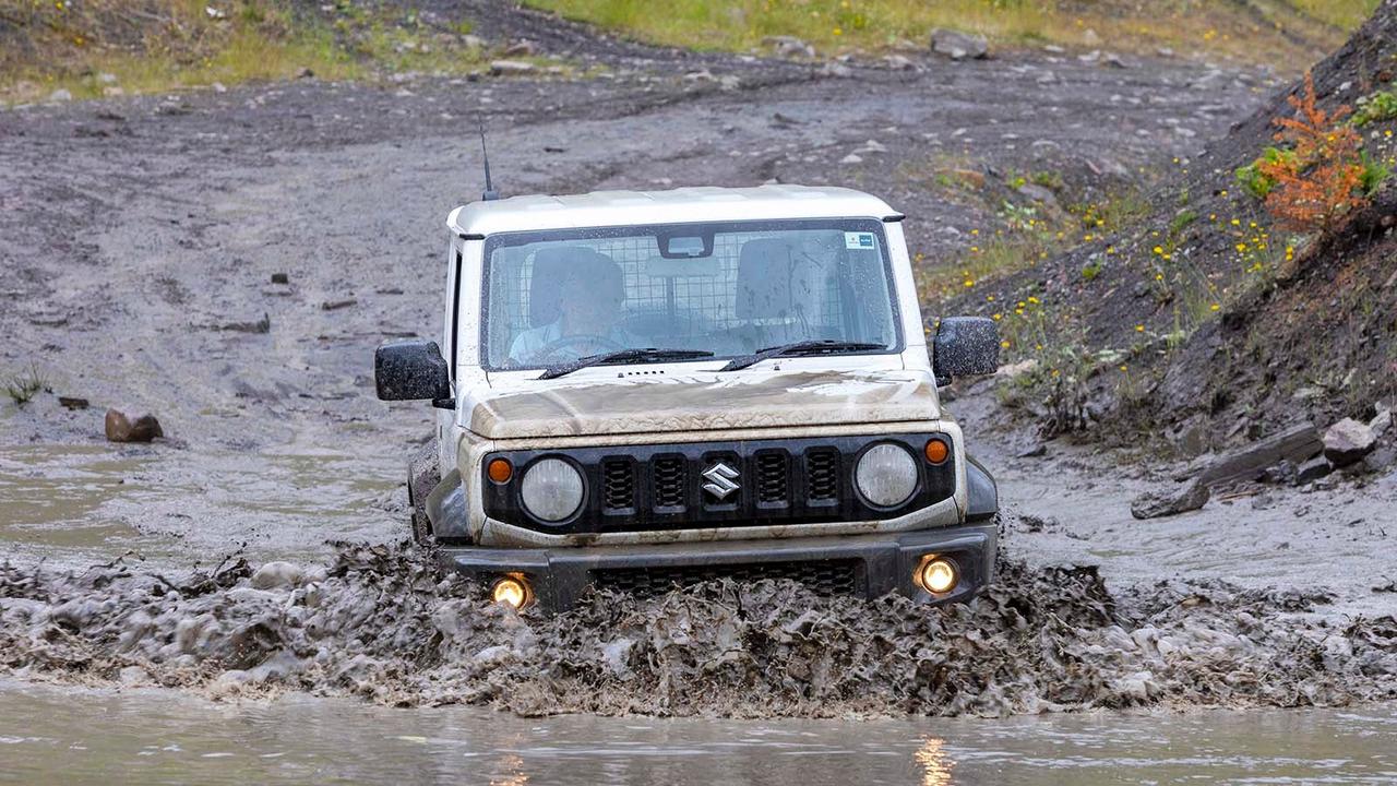 Suzuki Jimny in white, front-on driving through mud