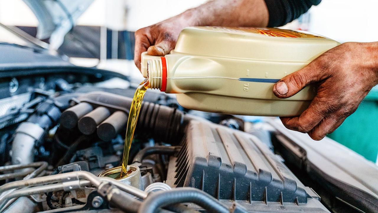 Mechanic pouring engine oil into a car