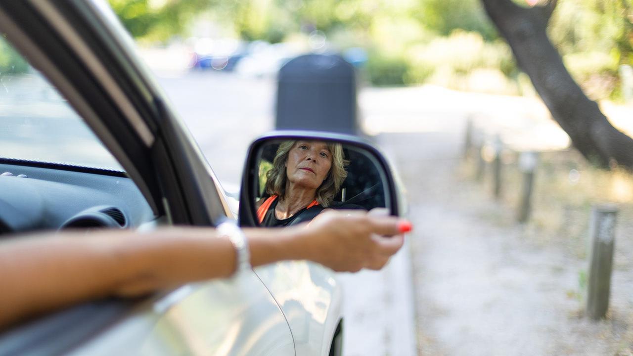 Driver checks her reflection in door mirror