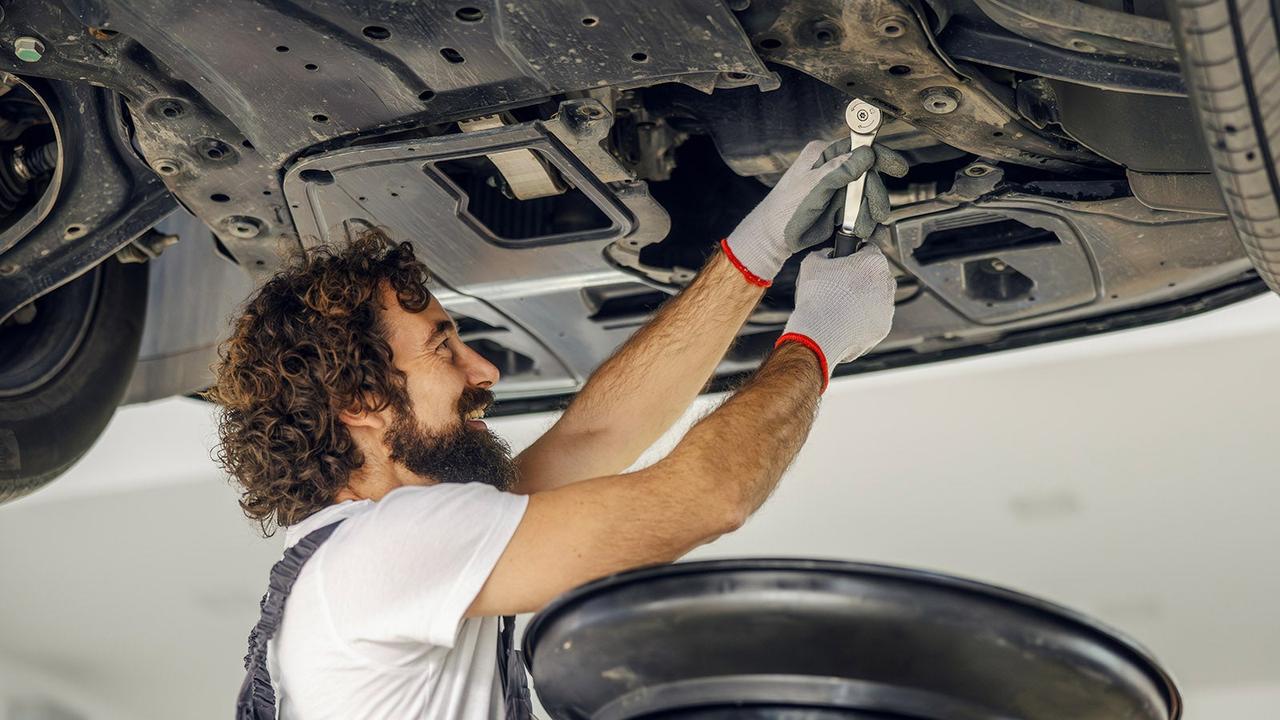 Mechanic undoing engine oil drain plug