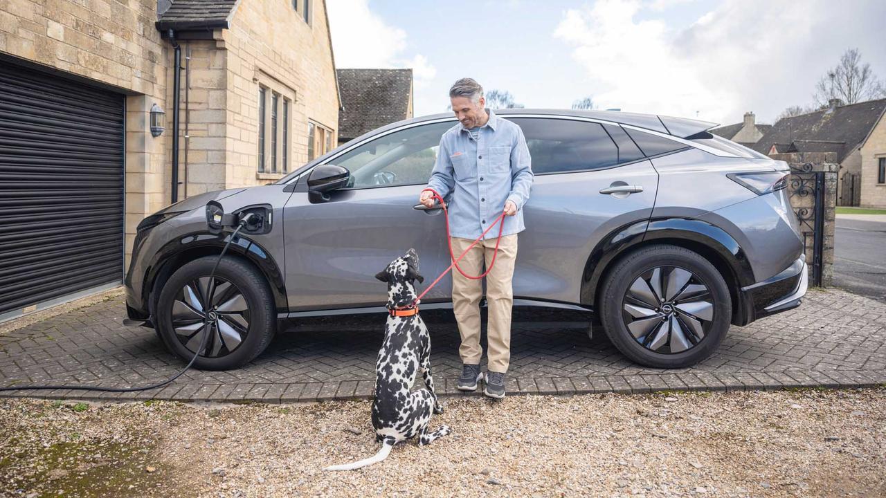 Man giving dog a treat in front of Nissan Ariya
