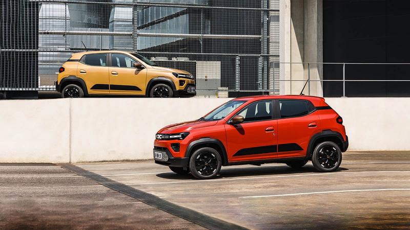 Pair of Dacia Spring cars static, yellow and red, parked in industrial setting