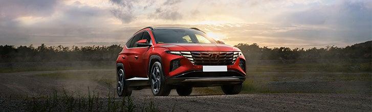 Red Hyundai Tucson driving away from a sunset